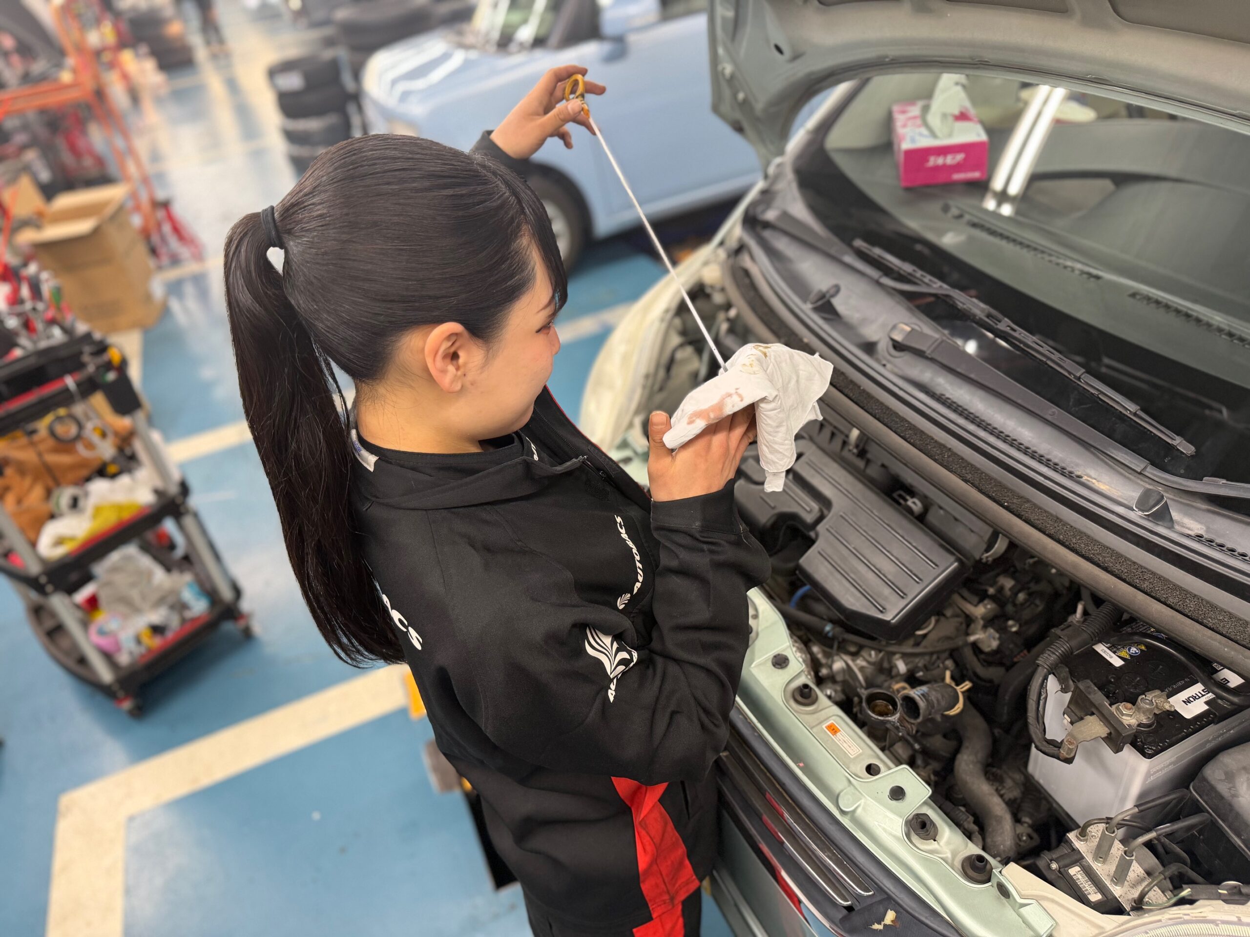 青空の下、満開の桜並木を走る白いミニバン。家族が窓から景色を楽しんでいる爽やかなドライブ風景