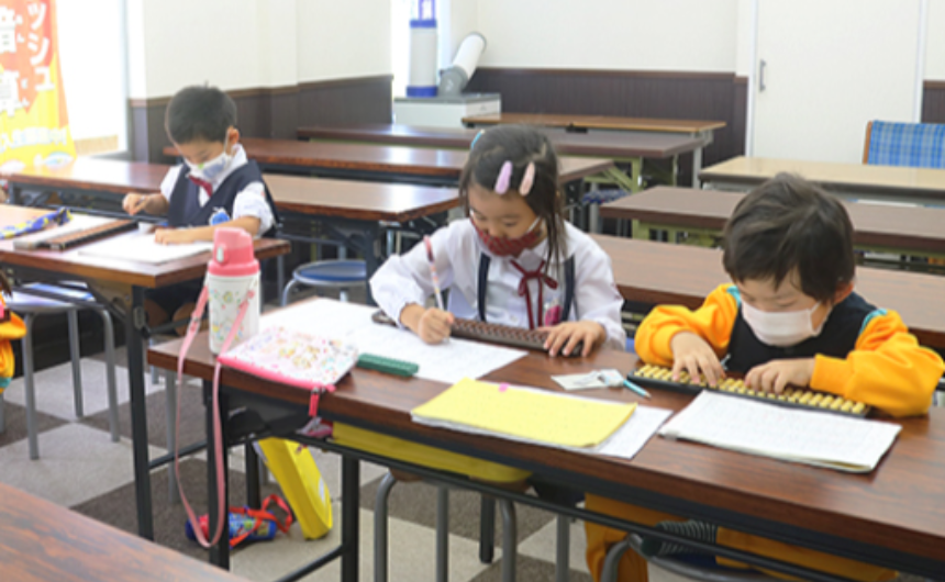 教室で先生が優しく指導している風景や、読み上げ算に集中する子供たちの明るい雰囲気の画像