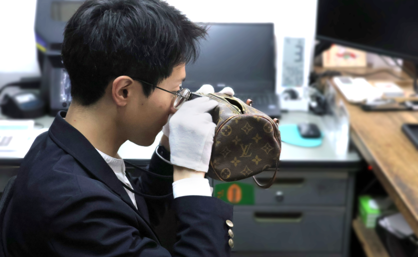 ルーペを使って丁寧にステッチや刻印を確認する鑑定士